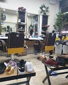 Barbershop interior with black and yellow chairs, mirrors, and shoes displayed on wooden benches.